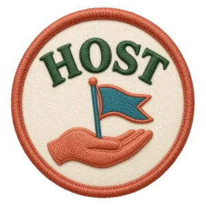 Verdant Ride Host badge: an embroidered patch, a hand holding a small flag, cream field with a rust border.